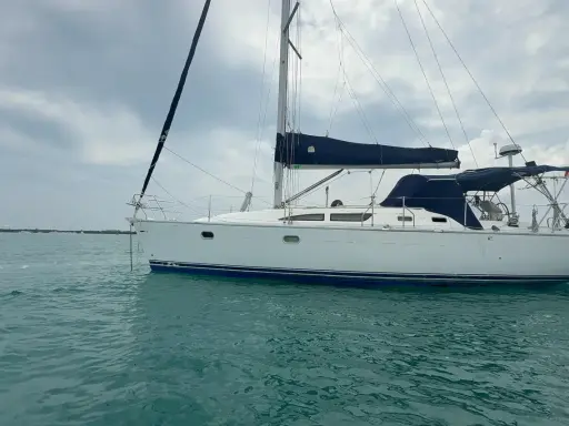 Voilier blanc à l'ancre, voiles bleues repliées. Un avis sur le Sun Odyssey 37, prêt pour l'aventure.