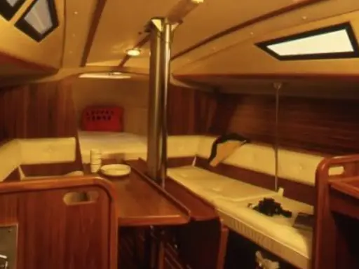 Intérieur chaleureux d'un voilier, avec banquettes en cuir crème, boiseries sombres et hublots. Le **selection 37 interieur** offre un espace confortable pour la vie à bord.