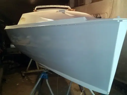 Le bateau Neptune 550, prêt pour sa nouvelle peinture, repose sur des supports dans un atelier.
