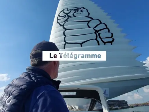 Un homme regarde une voile géante ornée du logo Michelin. Le Télégramme est affiché sur la voile.