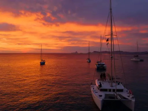 Coucher de soleil sur la mer avec des voiliers. Le tarif destruction bateau est une préoccupation pour certains, mais ici, la beauté règne.