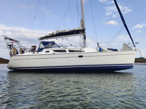 Un voilier Sun Odyssey 35, blanc avec une bande bleue, navigue paisiblement sur une mer calme. Les avis sur ce bateau sont positifs.