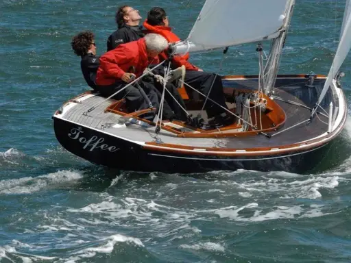 Le voilier "Toffee" navigue sur une mer agitée, quatre personnes à bord profitent de la balade.