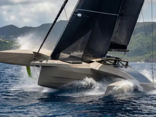 Un trimaran futuriste fend les vagues, ses voiles noires déployées. Un spectacle impressionnant, digne d'un "etape 21i avis" de course.