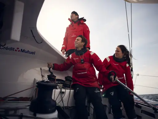 Amélie Grassi et son équipage en pleine action sur un voilier Crédit Mutuel. Le vent souffle, la mer est agitée.