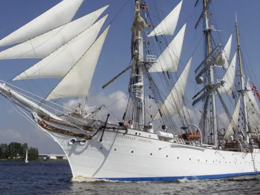 Le Statsraad Lehmkuhl, voilier blanc aux voiles gonflées, navigue fièrement, symbole du **general valor** des marins.