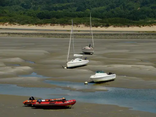 Trois voiliers et un bateau à moteur échoués sur la vase, avec un zodiac rouge au premier plan. Le **kelt 9** est l'un des voiliers.