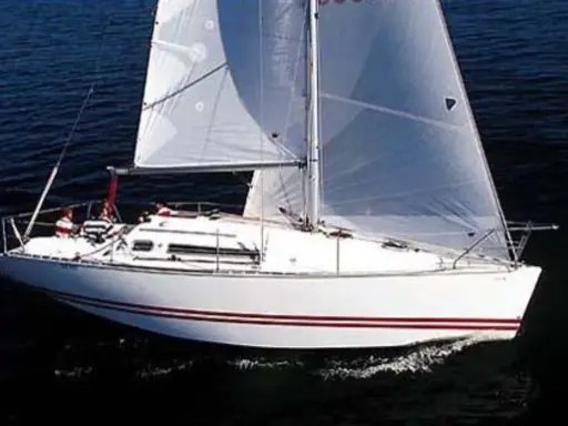 Voilier blanc à voiles gonflées, naviguant sur l'eau sombre. Les avis sur le Sun Fast 32 confirment sa rapidité.