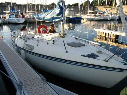 Deux personnes sur un voilier blanc, un Kelt 620, dans un port. Les avis sur ce bateau sont positifs.