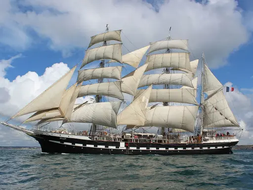 Le Belem, majestueux trois-mâts, navigue fièrement sous un ciel bleu et nuageux, rappelant les grandes traversées vers Bayonne.