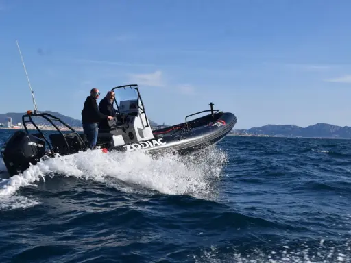 Deux hommes naviguent sur un Zodiac en Méditerranée. La météo marine méditerranée gratuite est idéale pour cette sortie en mer.