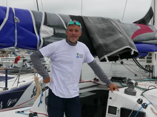 Gildas Mahé, skipper, pose sur son voilier, prêt pour une nouvelle aventure maritime.