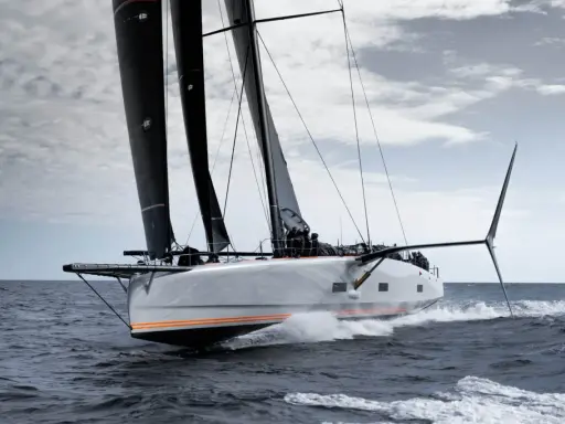 Le voilier Baltic 111 Raven fend les vagues, ses voiles noires gonflées par le vent.