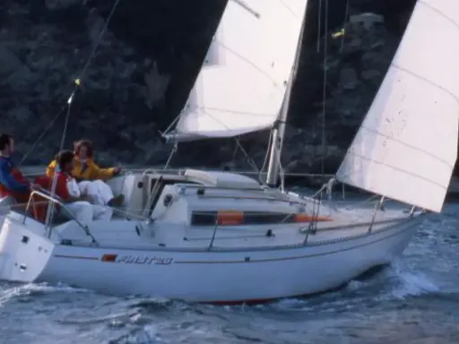 Trois personnes naviguent sur un voilier blanc, le "Pirat 26". Les voiles sont gonflées par le vent, créant une scène paisible.