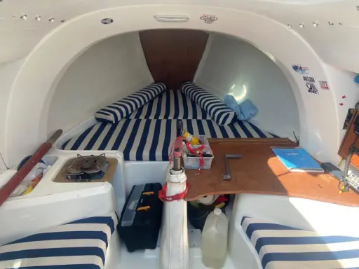 Intérieur du first 210, avec banquettes rayées bleu et blanc, réchaud, outils et bidon d'eau. Prêt pour l'aventure !