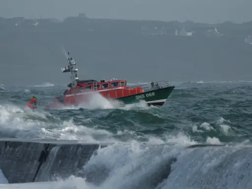 Bateau de sauvetage SNS 068 naviguant dans une mer agitée, affrontant la tempête. Les vagues déferlent sur la proue.