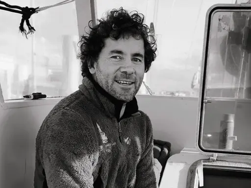 Sébastien Roubinet, un aventurier souriant, pose à l'intérieur d'un bateau, prêt pour sa prochaine expédition.