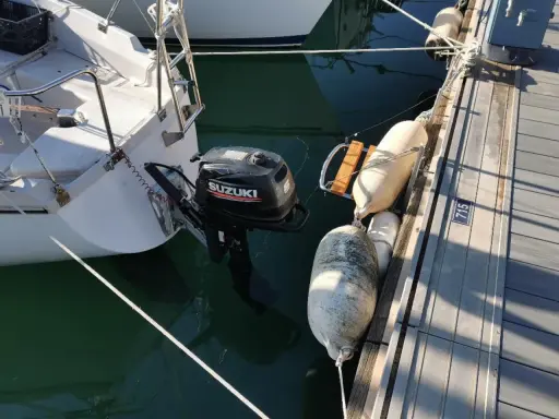 Un voilier "love love" amarré au ponton, avec un moteur Suzuki prêt à l'action. Des pare-battages protègent la coque.
