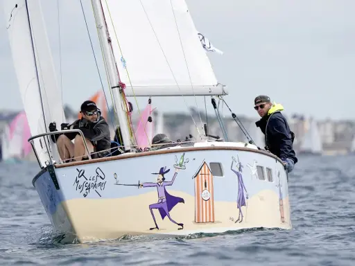 Un bateau muscadet décoré de personnages fantaisistes navigue sur l'eau, avec deux hommes à bord.