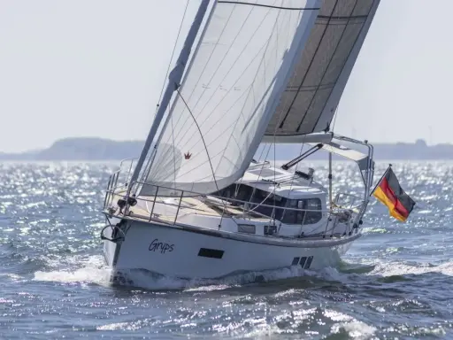 Le voilier Sirius 40 DS "Gryps" navigue sur une mer scintillante, pavillon allemand au vent.