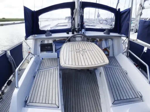 Cockpit d'un Nauticat 33 avec table en teck ornée d'une rose des vents. Détails techniques visibles.