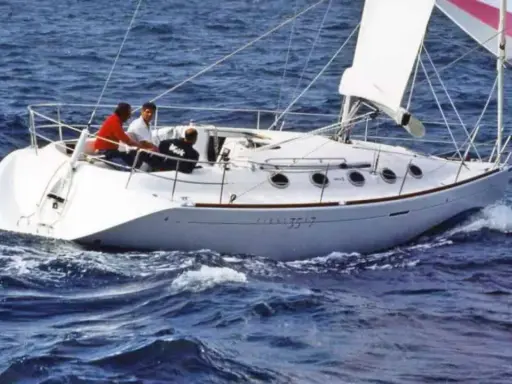 Voilier blanc naviguant sur une mer agitée. Trois personnes à bord. Le numéro 3517 est visible sur la coque.