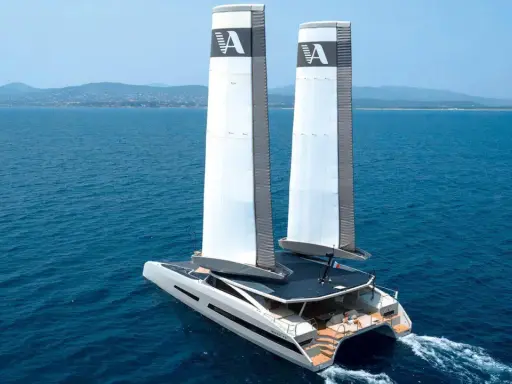 Le catamaran de luxe MODX 70 navigue sur une mer bleue, ses deux voiles imposantes portant le logo "A".