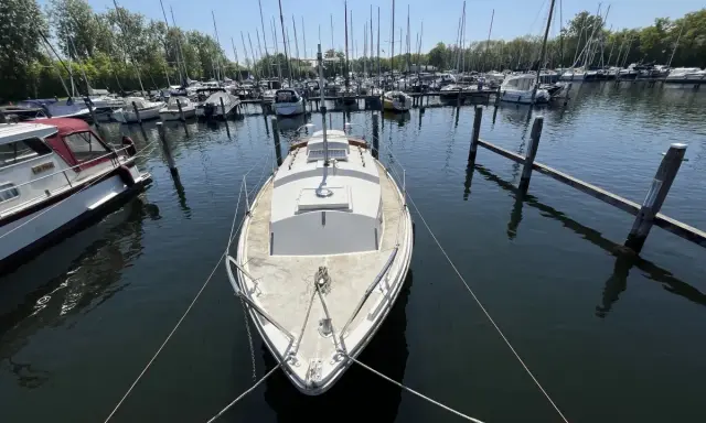 Un voilier blanc, type Westerly Centaur, est amarré dans un port. D'autres bateaux sont visibles au loin.