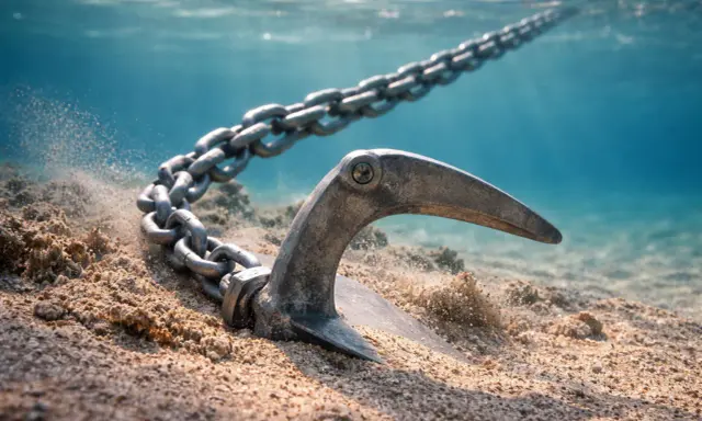 Ancre s'enfonçant dans le sable, sa chaîne s'étendant vers la surface. Le poids de l'ancre par rapport au bateau est essentiel pour le maintenir stable.