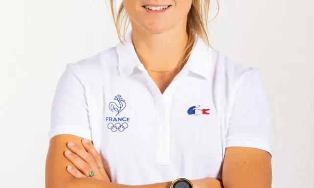 Manon Audinet, athlète française, porte un polo blanc avec les anneaux olympiques et le coq gaulois.