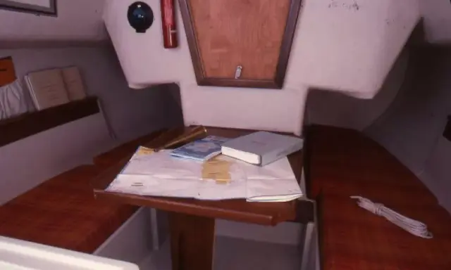 Vue du premier 22 intérieur d'un voilier, avec une carte marine, des livres et un compas.