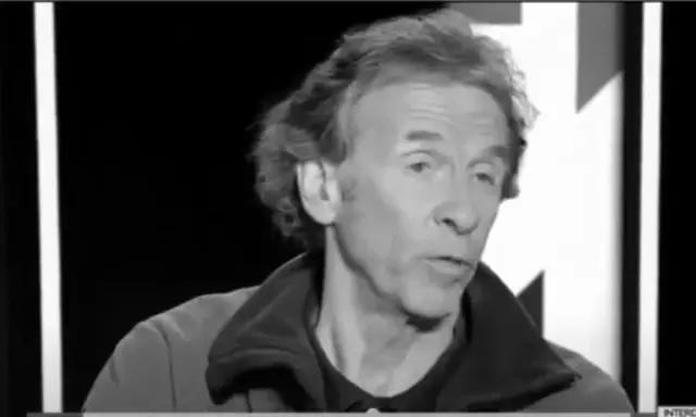 Portrait en noir et blanc d'Éric Loizeau, homme aux cheveux ondulés, parlant dans un micro.