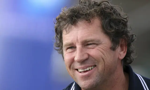 Lionel Lemonchois, skipper souriant, cheveux bouclés, sur fond bleu.