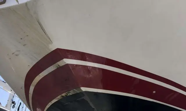 Nettoyage coque bateau acide chlorhydrique : la partie immergée du bateau, avec des traces de salissures et de la peinture rouge et blanche.