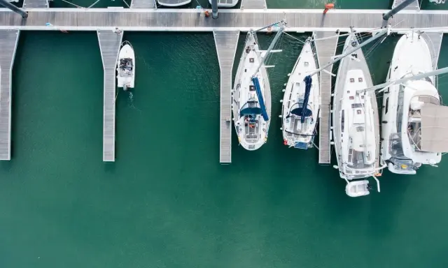 Vue aérienne d'un port avec plusieurs voiliers amarrés. Le coût de l'assurance bateau dépend de nombreux facteurs.