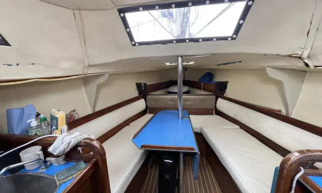 Intérieur d'un voilier, avec banquettes, table bleue et évier. Un coin de fantasia voilier interieur prêt pour l'aventure.