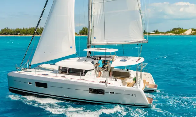 Catamaran Lagoon 42 naviguant sur des eaux turquoise. La fiche technique de ce voilier de luxe promet des croisières inoubliables.