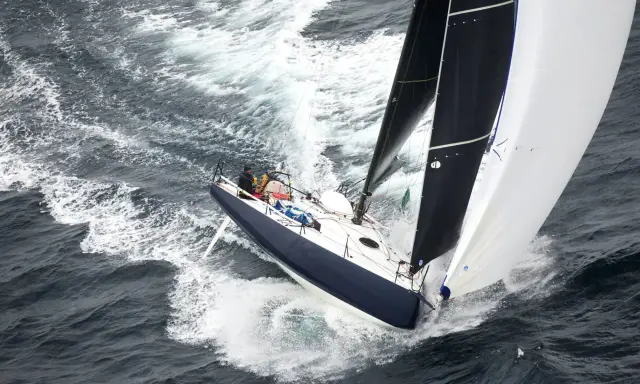 Un voilier de course fend les vagues, ses voiles noires et blanches gonflées par le vent. On dirait qu'il nous montre comment naissent les bateaux, prêts à conquérir l'océan.