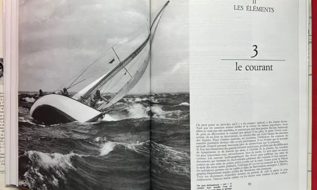 Un voilier navigue dans une mer agitée, ses voiles gonflées par le vent. Alain Gliksman, passionné de voile, admire cette scène.