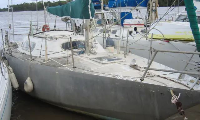 Voilier gris amarré, prêt pour une brise de mer 31. Voiles vertes et bleues, cordages et bouées.
