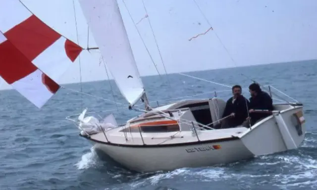 Deux hommes naviguent sur un voilier blanc, le "Esterel", avec des voiles rouges et blanches. Les premiers 22 avis sur ce bateau sont probablement très positifs.
