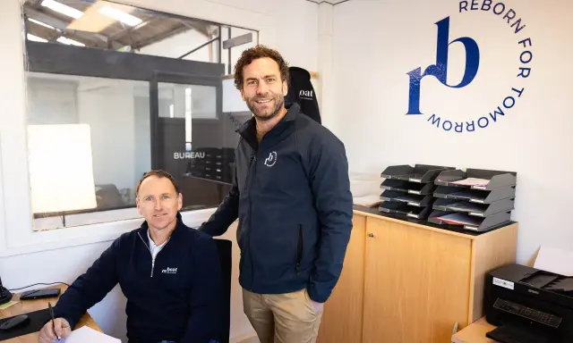 Dimitri Caudrelier et son collègue dans leur bureau, avec le logo "Reborn for Tomorrow" au mur.