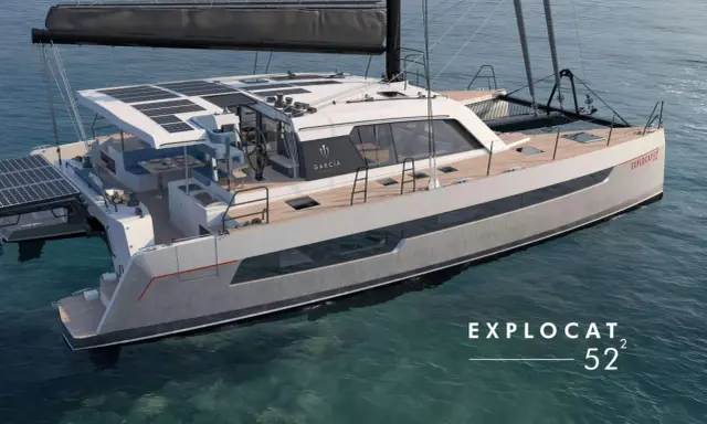 Un catamaran de luxe, un **deriveur integral** moderne, navigue sur des eaux bleues claires. Panneaux solaires sur le toit, design épuré.