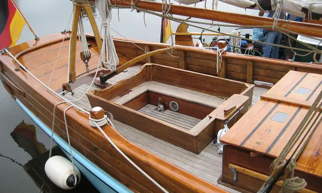 Le cockpit bateau en bois verni, avec ses cordages et sa bouée blanche, prêt pour une nouvelle aventure.
