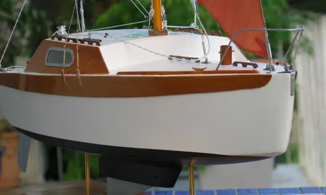 Modèle de voilier corsaire, coque blanche et bois verni, voile orange. Fiche technique détaillée.