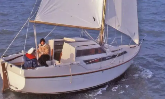 Un voilier Evasion 22 navigue sur une mer agitée, deux personnes à bord profitent de la brise.
