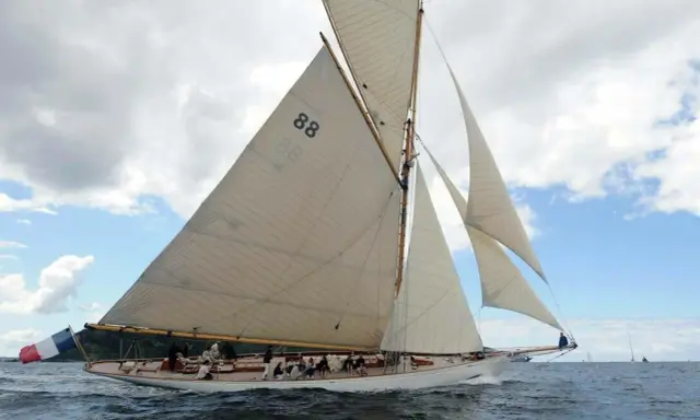 Le voilier "Moonbeam 4" navigue sur une mer agitée, ses voiles blanches gonflées par le vent.