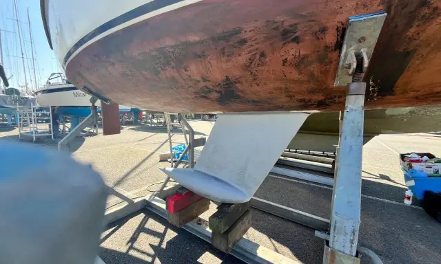 Vue du dessous d'un voilier sur bers. Le safran est visible, prêt pour l'étape 22 de la fiche technique.