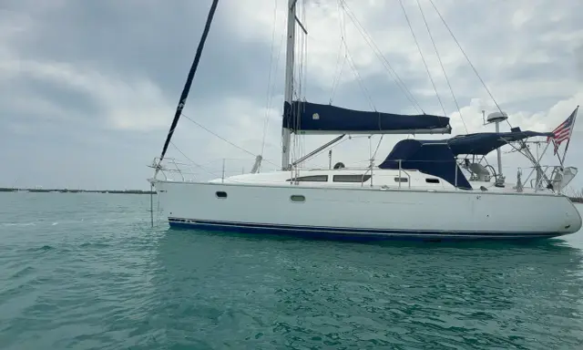 Voilier blanc à l'ancre, voiles bleues repliées. Un avis sur le Sun Odyssey 37, prêt pour l'aventure.