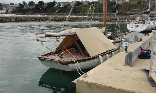 Un cotre de Carantec, "Le Vieux Gui", est amarré au port. Une autre voile blanche est visible à côté.